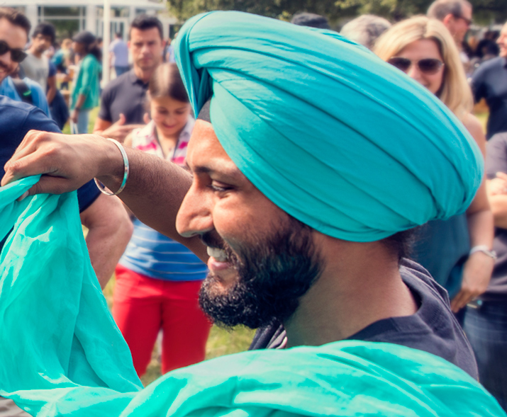 Foto eines lächelnden Mannes mit Turban, der einer anderen Person den Turban wickelt.