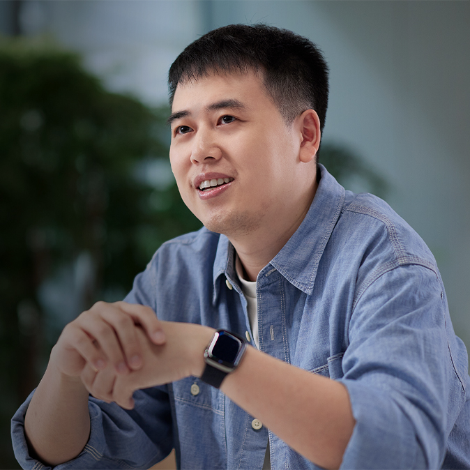  식물로 가득한 실내 공간에 앉아 있는 Ken.