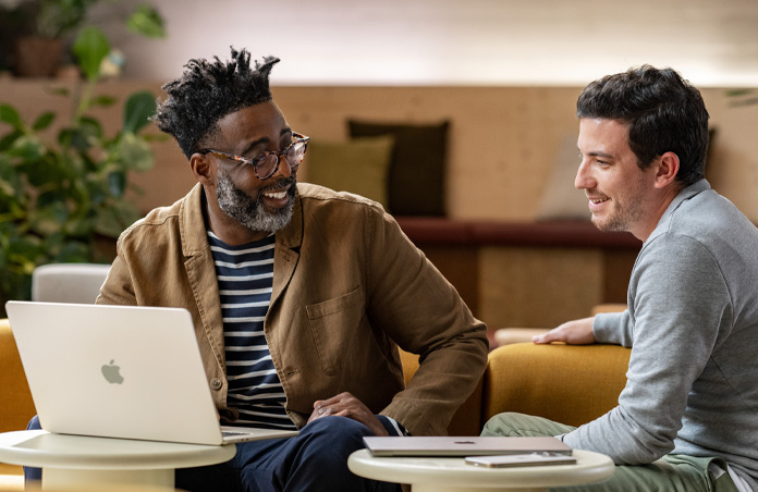 Un MacBook ouvert sur une table devant une personne souriante