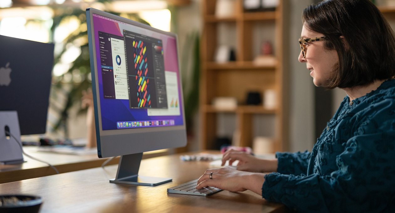 Une personne dans un bureau travaille sur un iMac affichant une app de design colorée