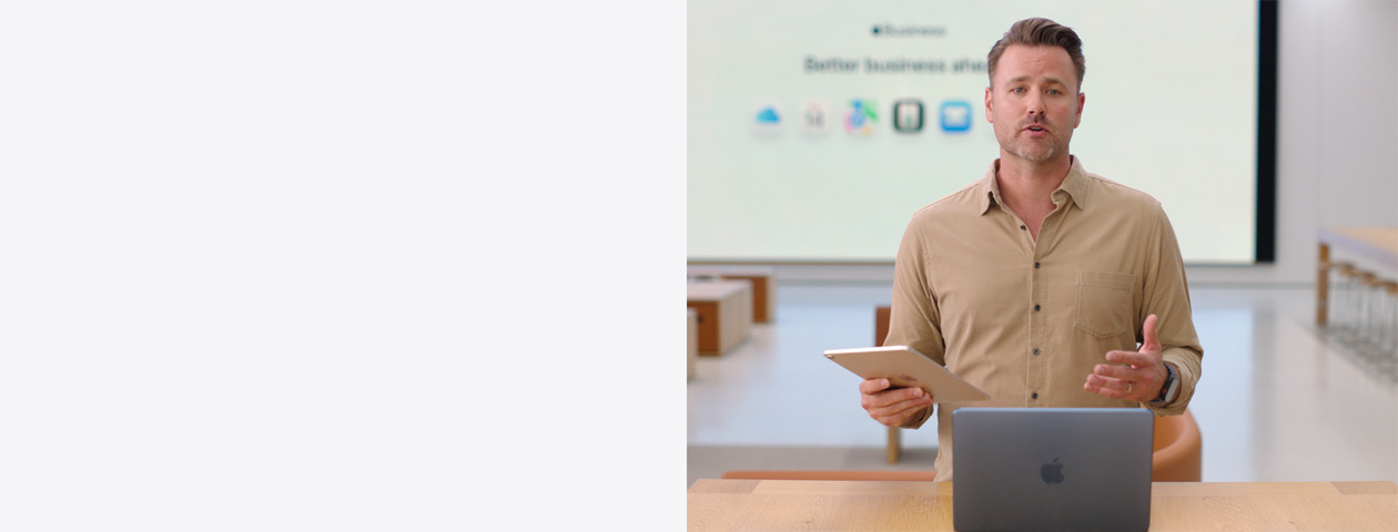 El presentador habla mientras hace referencia a un iPad, y al fondo se muestra una presentación y varios íconos de apps para empresas en una pantalla grande.