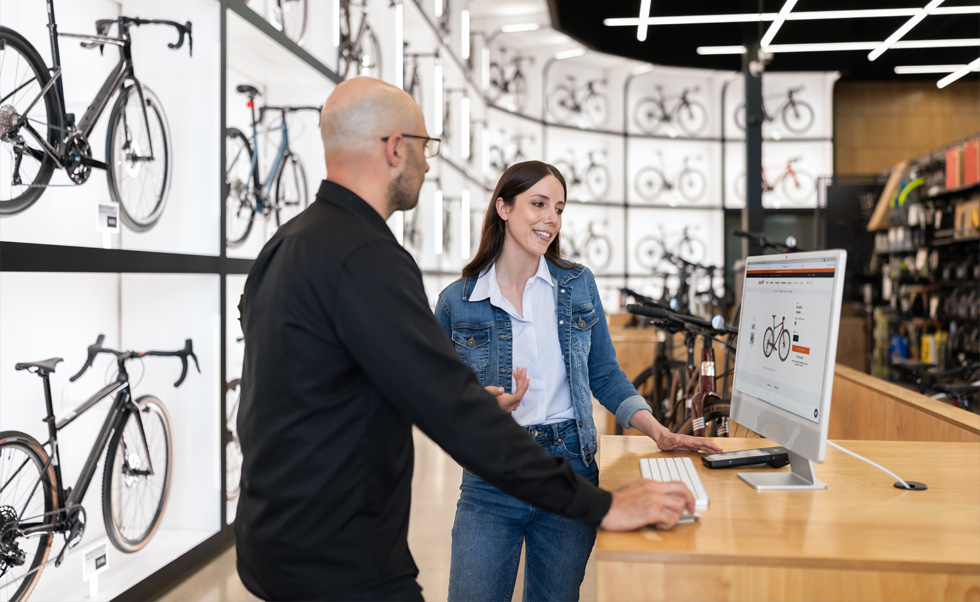 Julien Sicuro, gerente de tienda, ayuda a una clienta a escoger una bicicleta en la nítida pantalla Retina de una iMac.