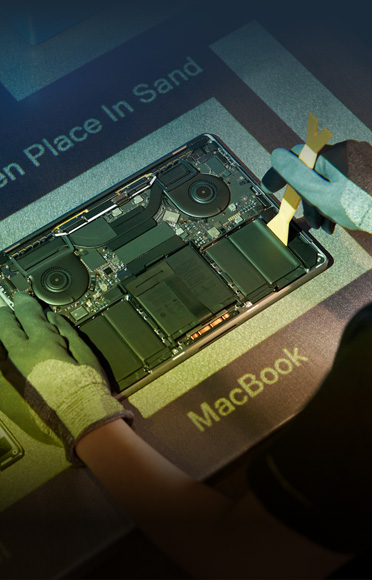 Des mains gantées désassemblent un MacBook, les composants internes sont visibles