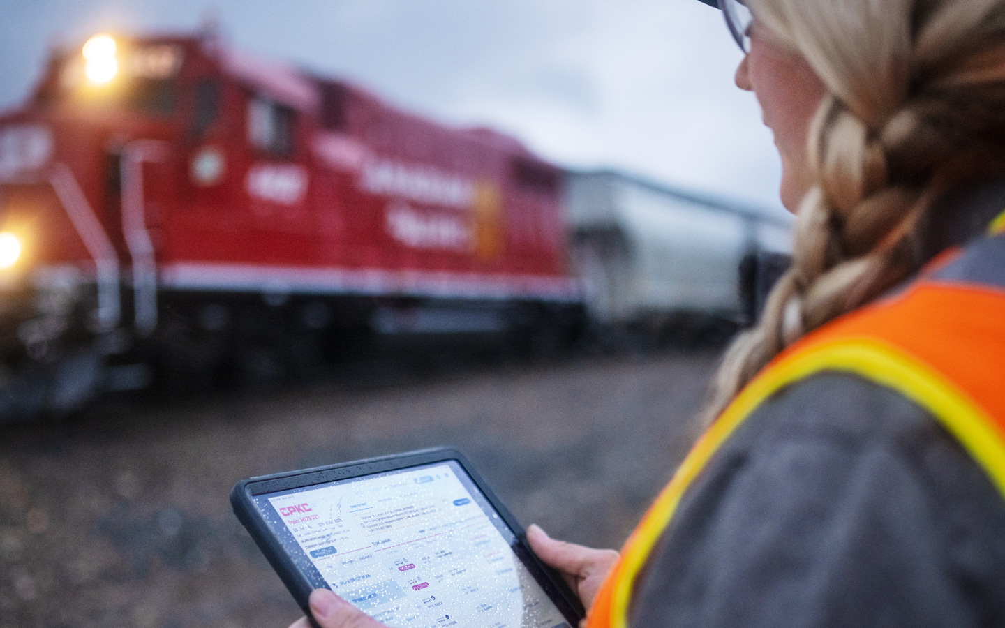 Un trabajador del ferrocarril consulta los horarios de los trenes en el iPad junto a un deposito ferroviario