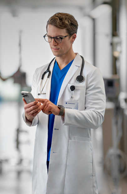 Un medico che guarda il suo iPhone in un ospedale, per consultare l’evoluzione clinica di una persona ricoverata.