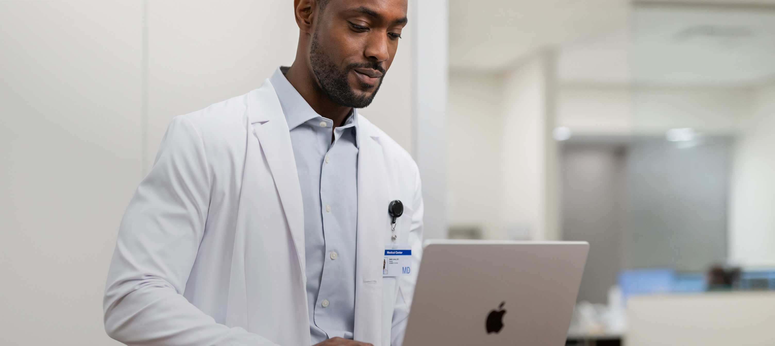 Ein Arzt, der im Krankenhaus auf seinem MacBook Pro arbeitet.