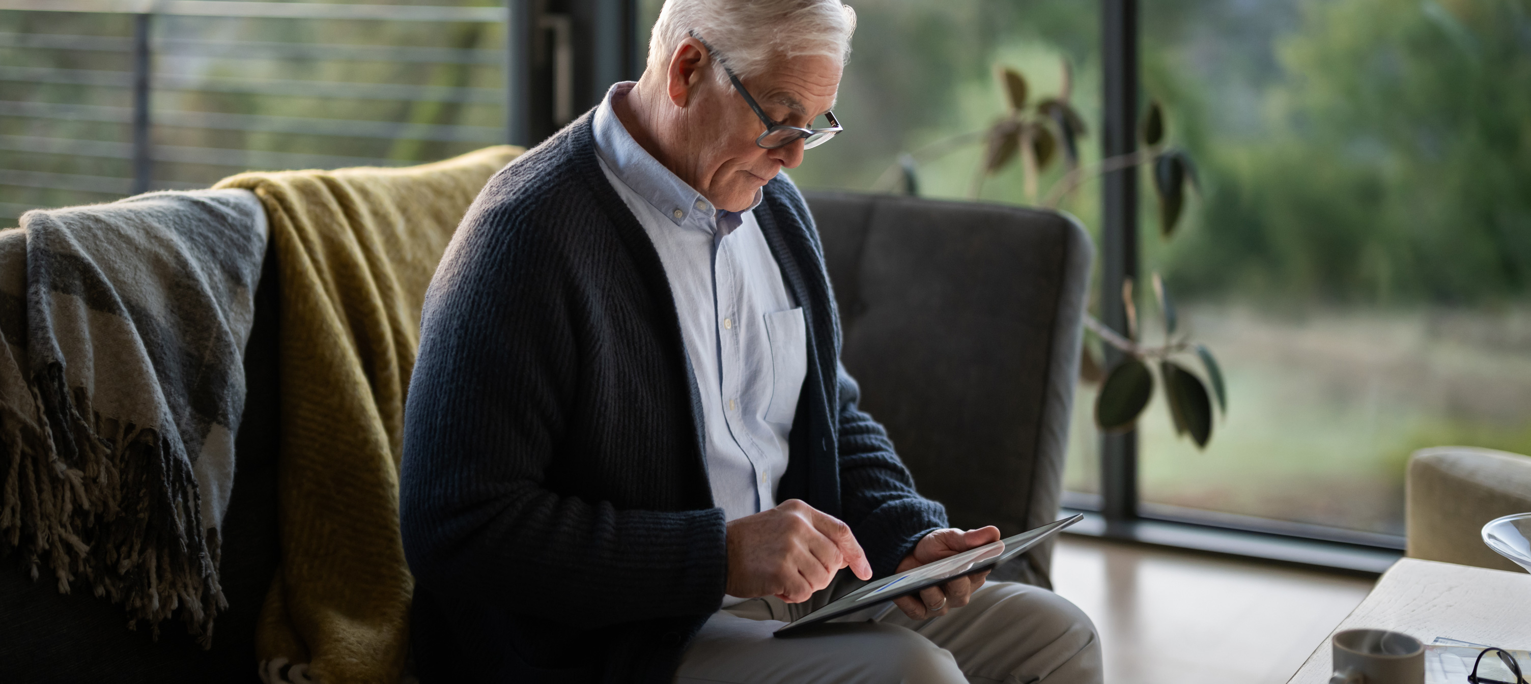 ソファに座ってiPadを見ている年配の男性