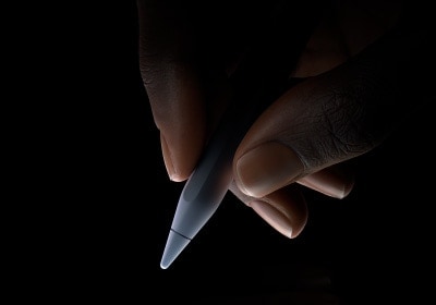 Une main tenant la partie inférieure d’un Apple Pencil Pro entre le pouce et l’index, en position d’écriture.
